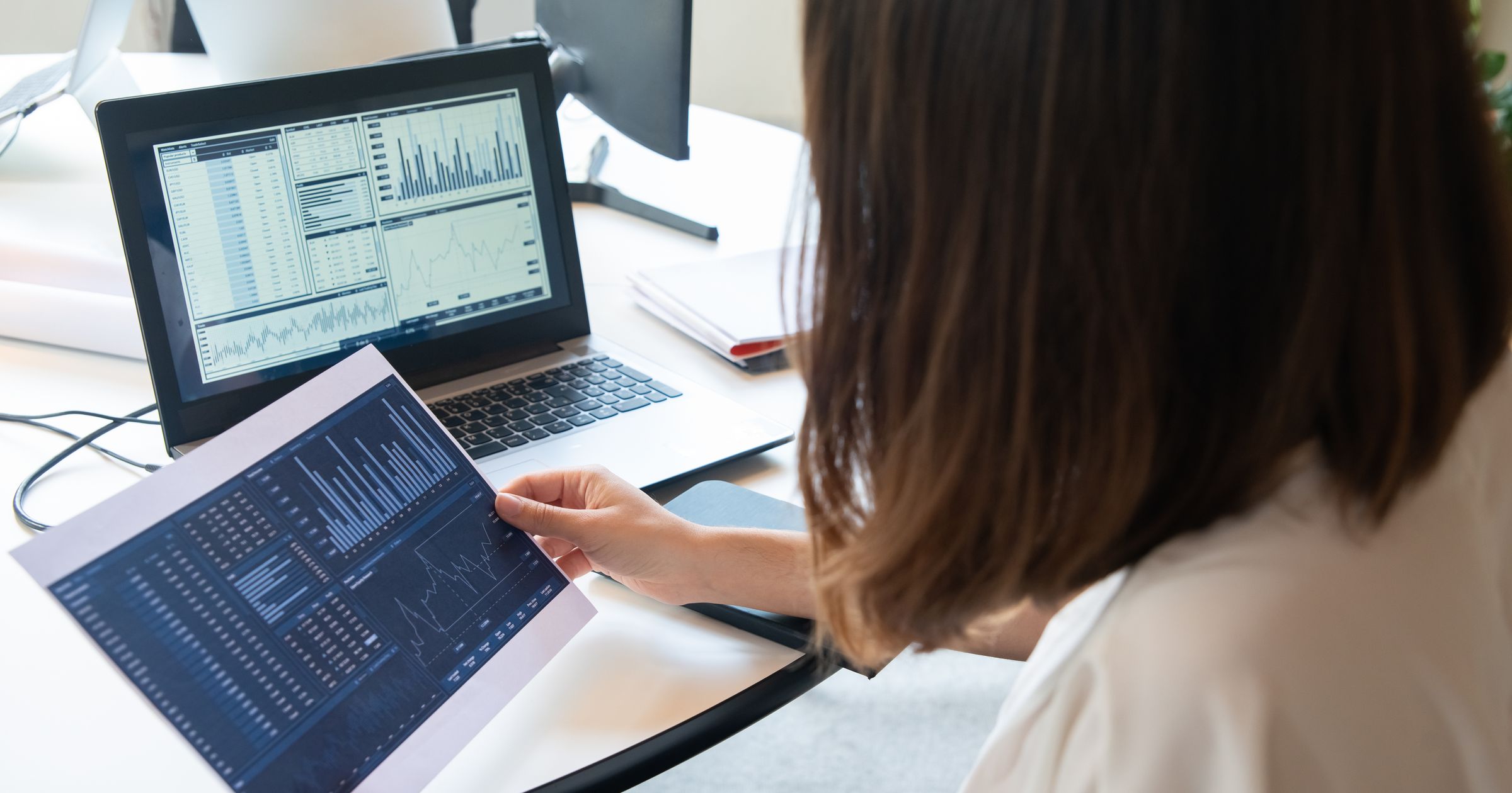 A laptop on a modern studio desk displaying an analytics dashboard with cost and revenue breakdown charts.