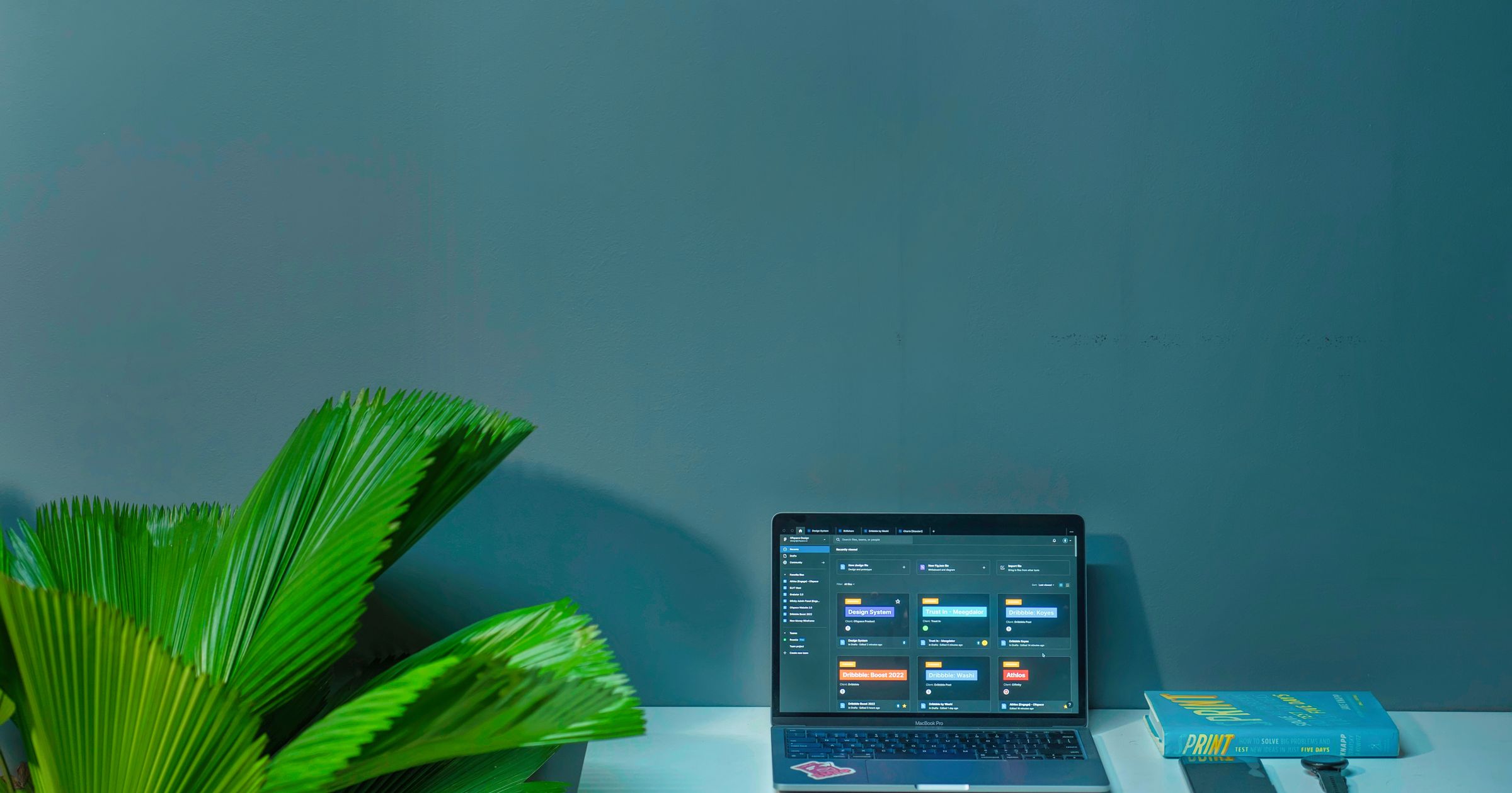 A small agency desk with a laptop, notebook, and printed project notes