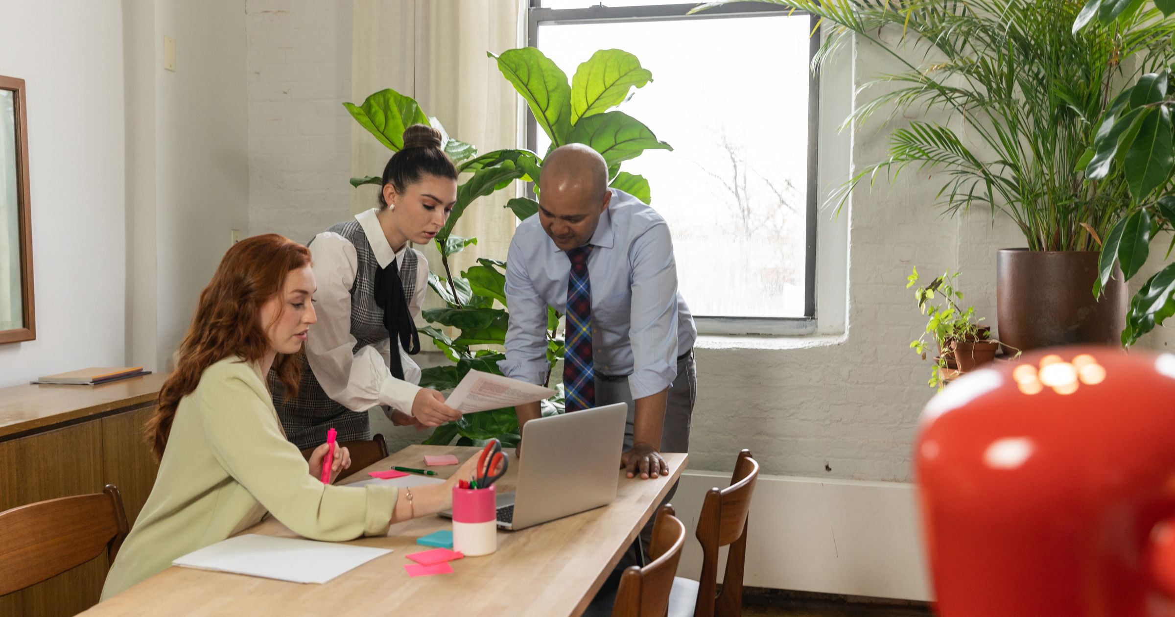 Two people looking at a laptop and a printed timesheet at a desk