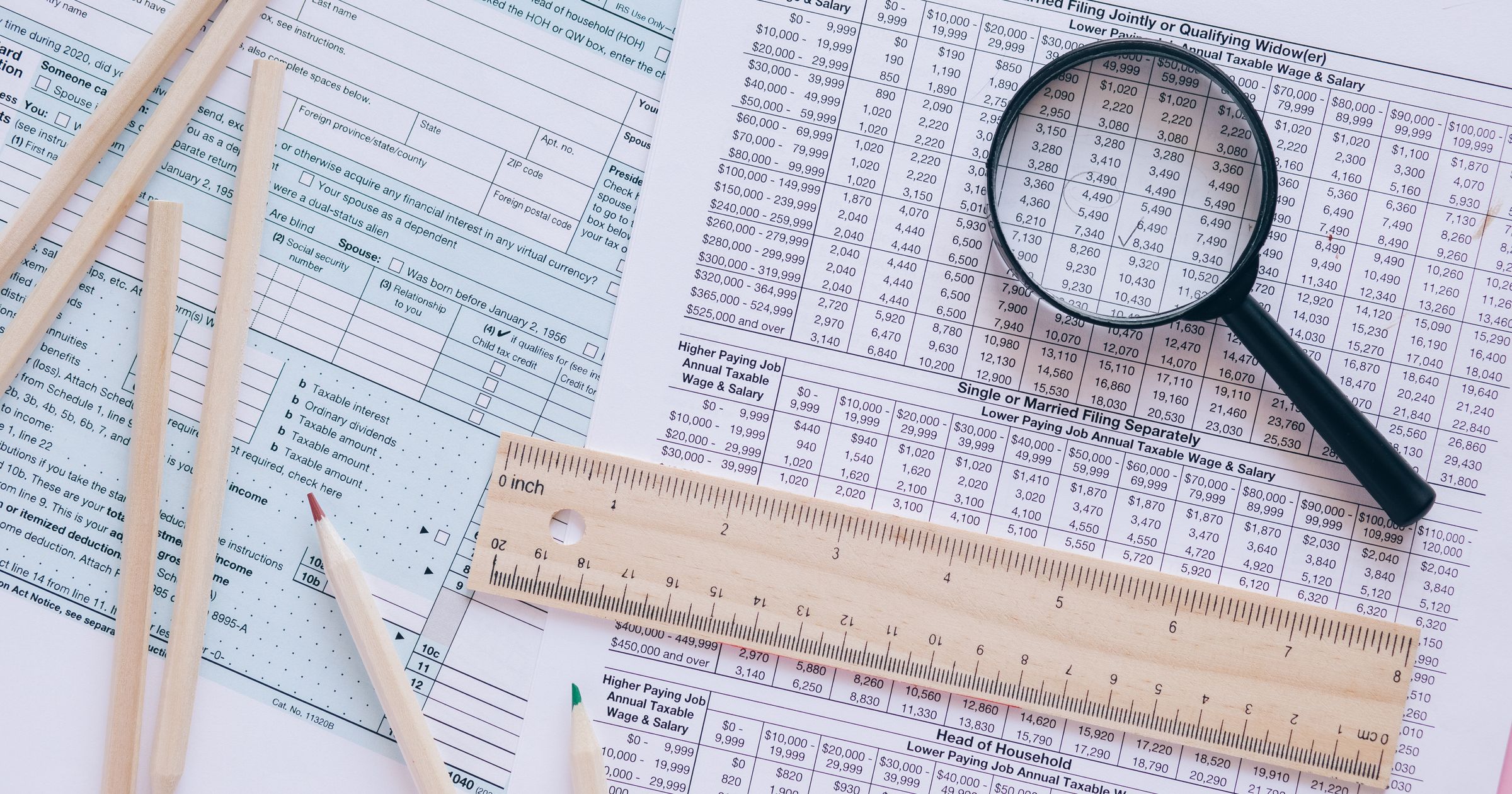 A person reviewing invoice lines on a laptop beside a notebook and calculator